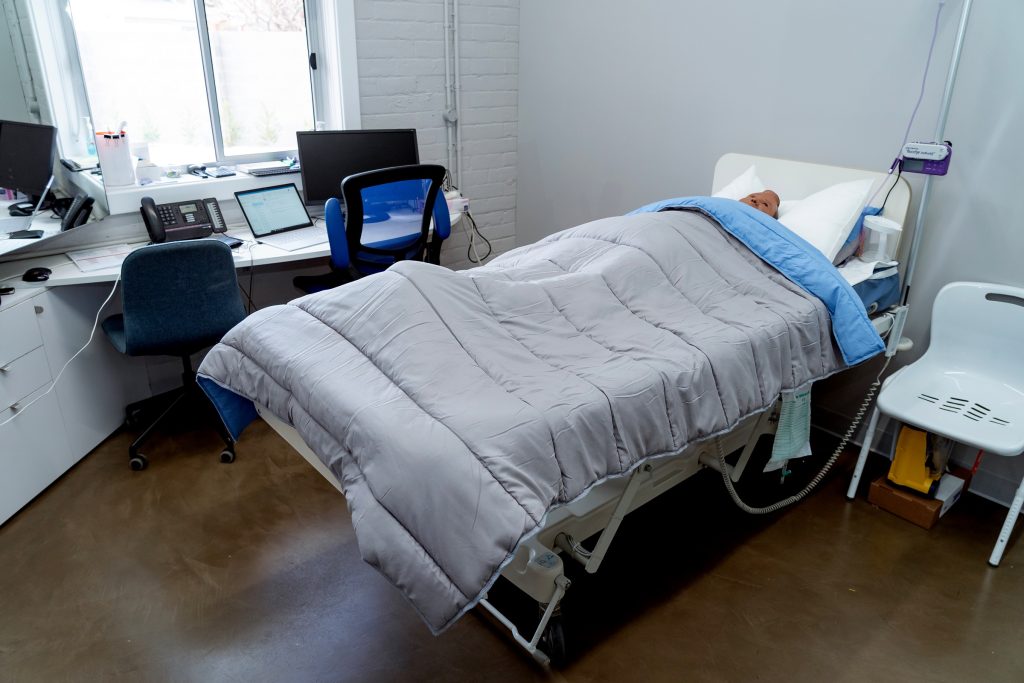 A staged bedroom, with a bed and chair to allow disability support workers to practice clinical skills during their training course.