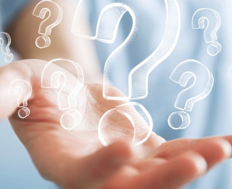 Question marks of various sizes sitting in the outstretched palm of a man wearing a blue shirt