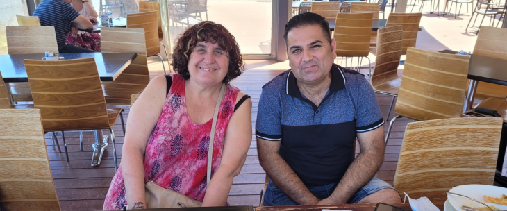 Smiling female NDIS participant sitting in a cafe, supported by her Enhanced Lifestyles Disability Support Worker.