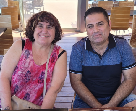 Smiling female NDIS participant sitting in a cafe, supported by her Enhanced Lifestyles Disability Support Worker.