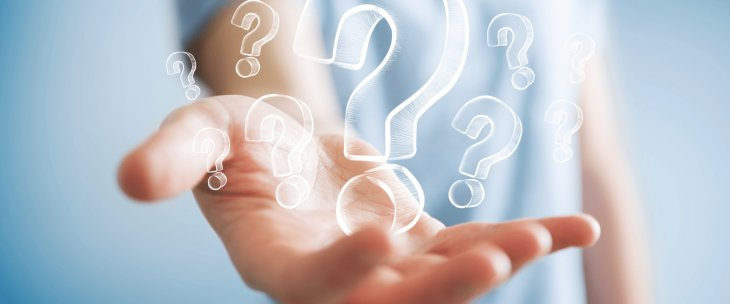 Question marks of various sizes sitting in the outstretched palm of a man wearing a blue shirt