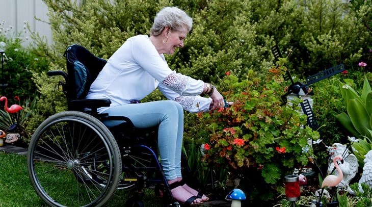 A female NDIS participant sitting in her garden pruning her flowers